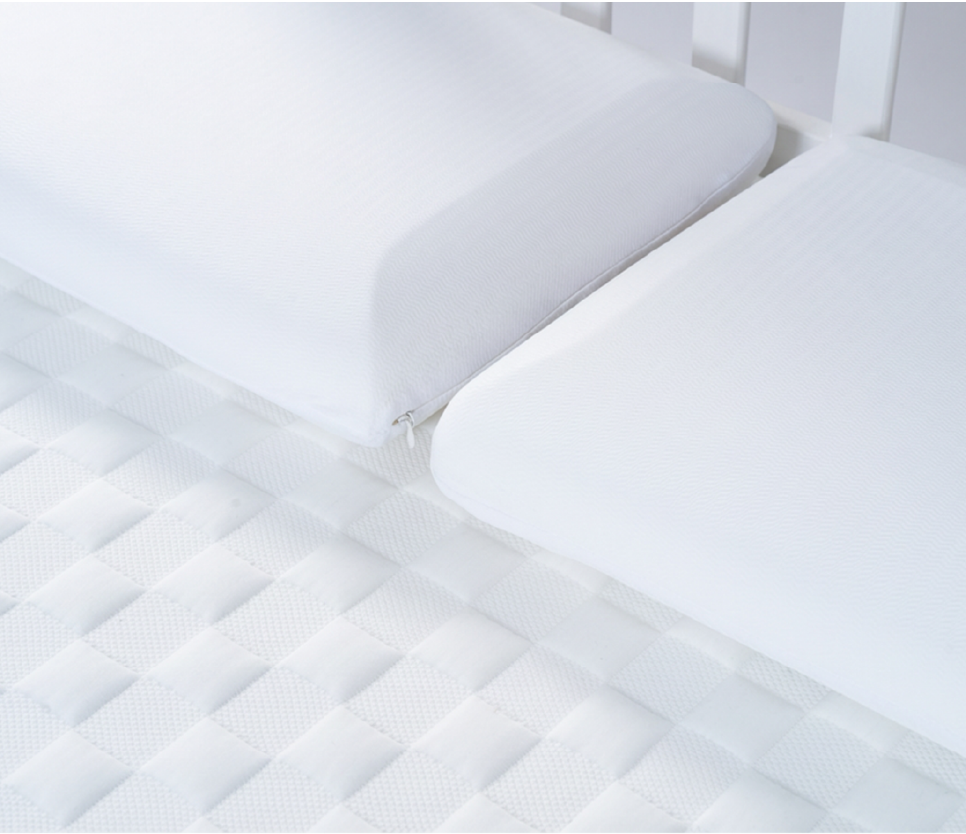 Close-up of a white mattress pad with quilted pattern on a bed.