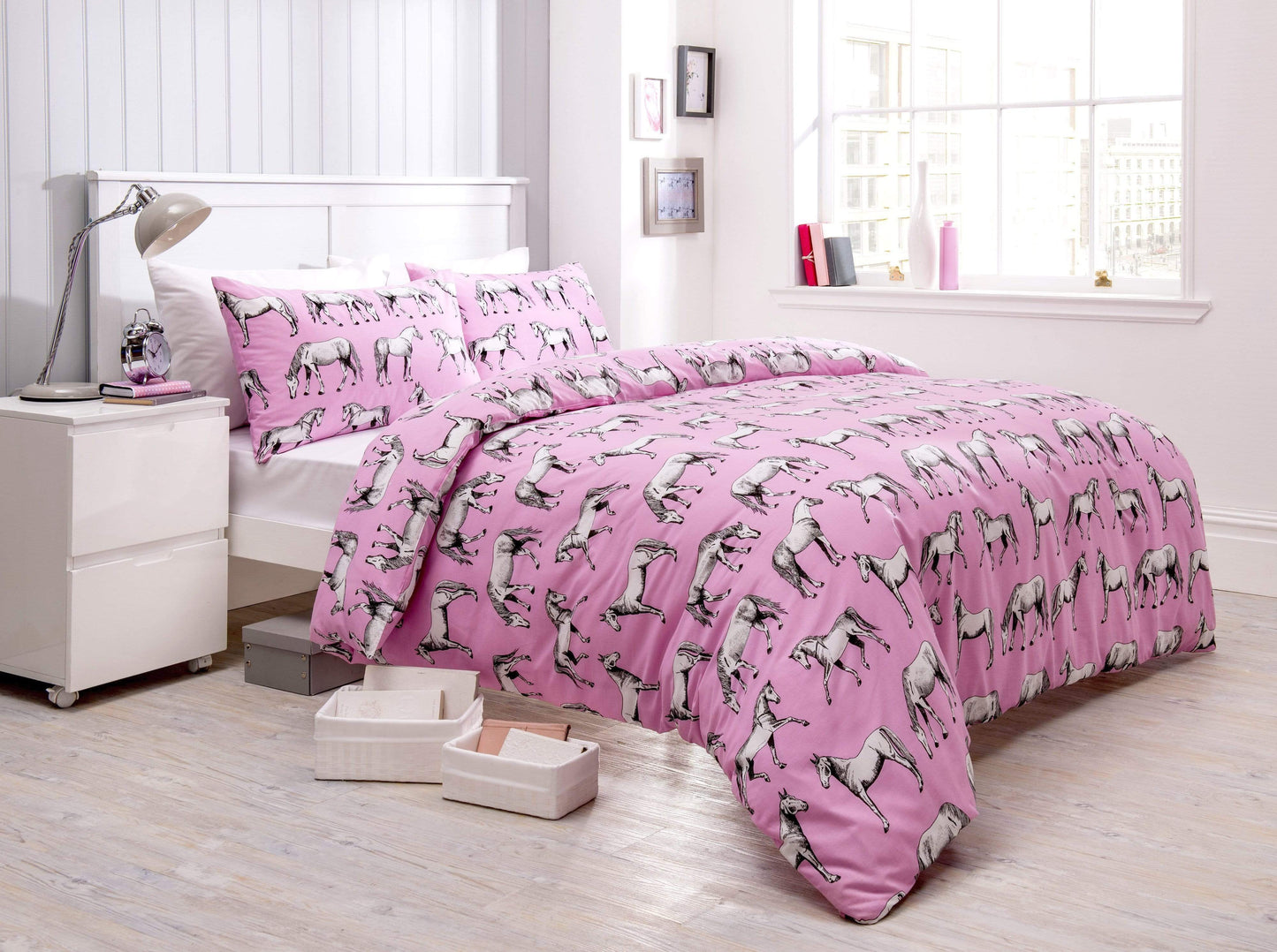 Pink bedspread with horse pattern on a bed in a bright bedroom.