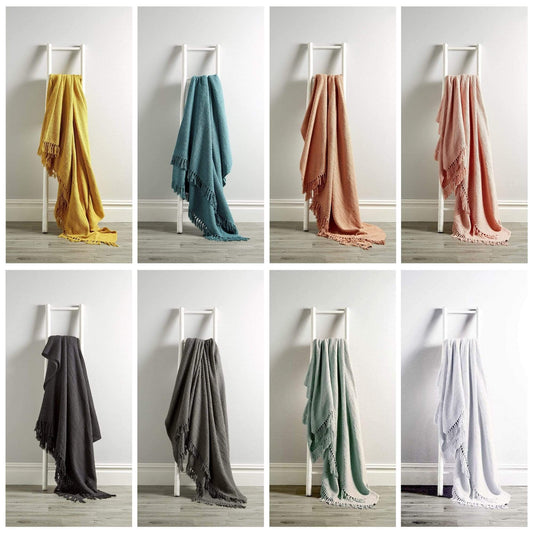 Set of eight scarves in various colors displayed on a white chair against a neutral background.
